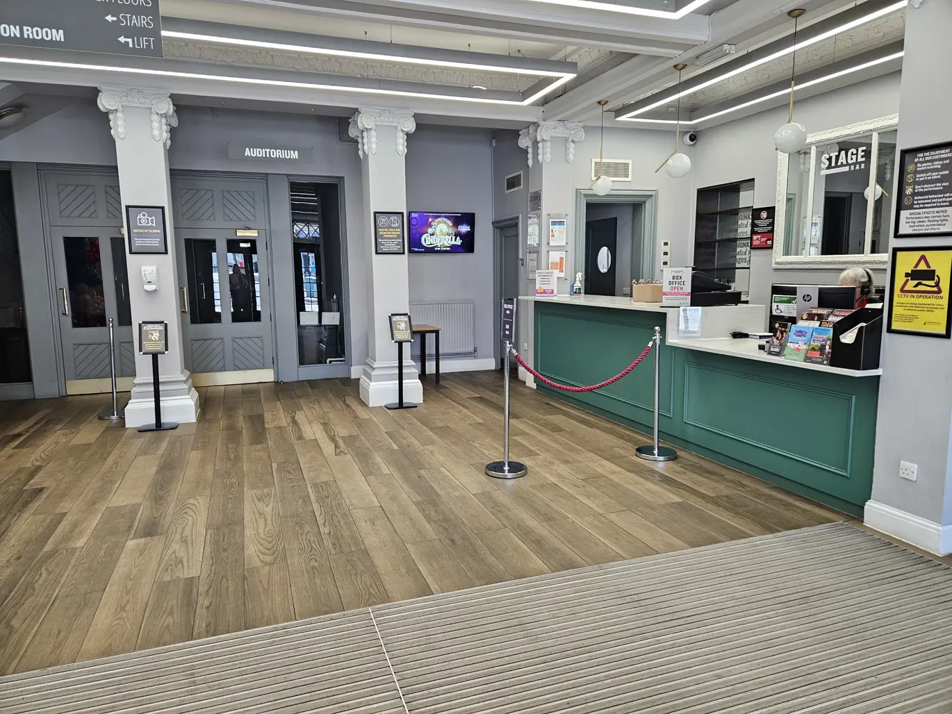 Winding Wheel Theatre box office and bar with wooden coloured floor and green coloured counter. Has a modern look.